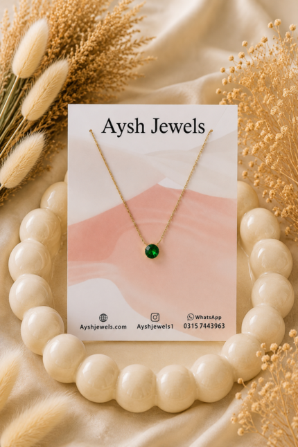Gold chain necklace featuring a brilliant, round-cut emerald green crystal pendant.